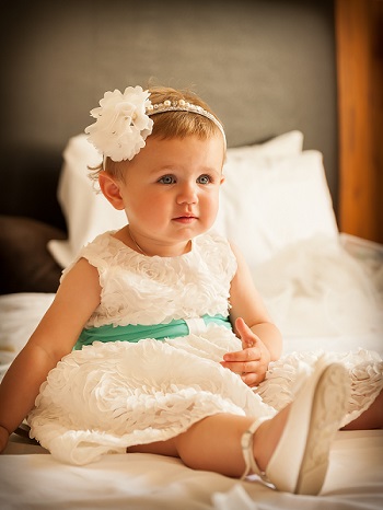 a picture of a baby girl in a flower girl outfit